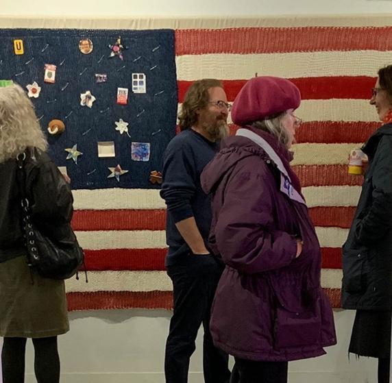 People in front of the Home of the Brave flag